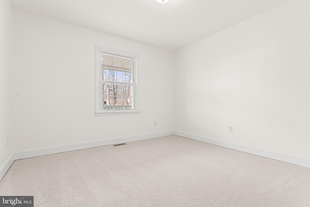 unfurnished room featuring visible vents, light colored carpet, and baseboards