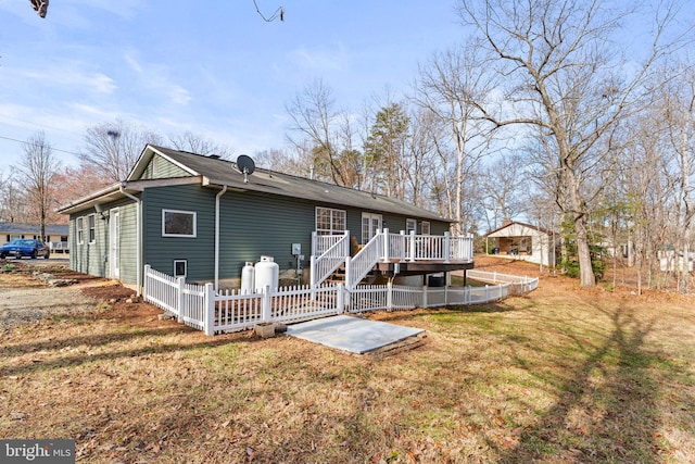 back of property featuring a lawn, a wooden deck, and fence