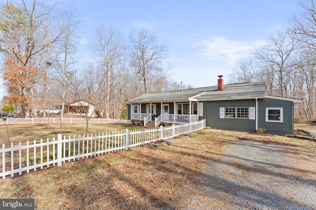 view of front of home with a fenced front yard, gravel driveway, a porch, and a chimney