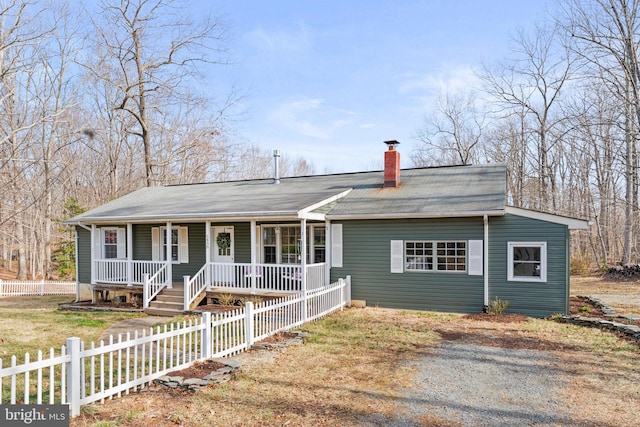 view of front of home featuring a fenced front yard, a porch, and a chimney