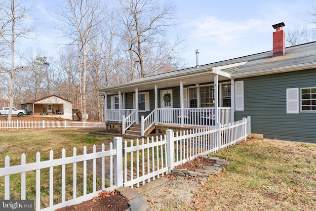 ranch-style home with a front lawn, covered porch, a fenced front yard, and a chimney