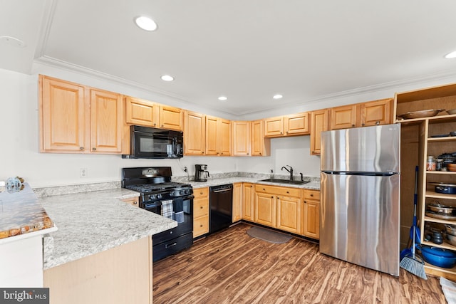 kitchen with light brown cabinetry, black appliances, and a sink