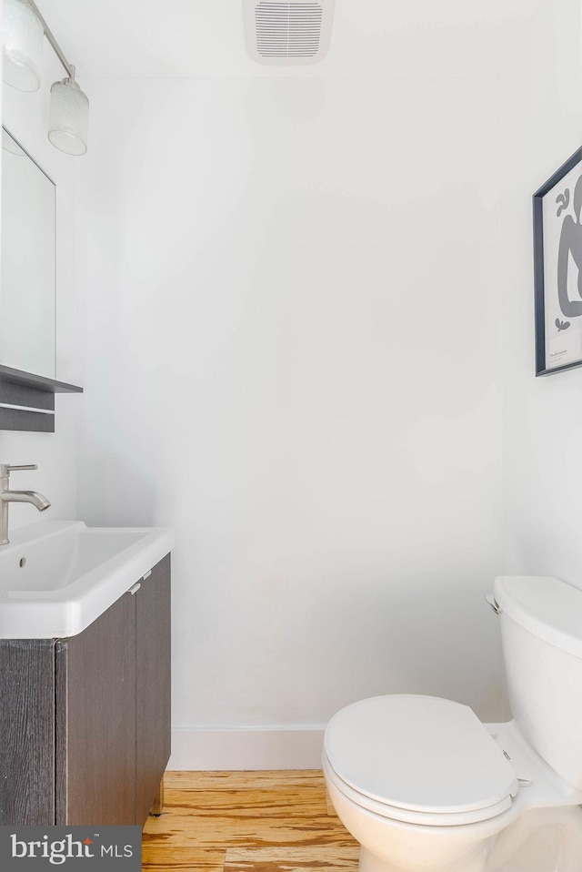 bathroom with hardwood / wood-style flooring, vanity, and toilet