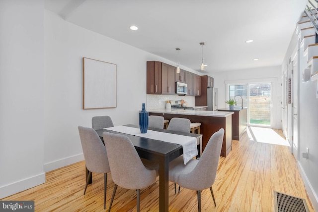 dining room featuring sink and light hardwood / wood-style floors