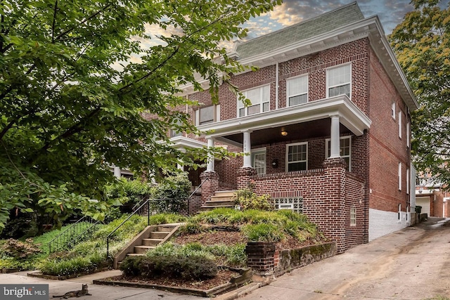 view of front of property with stairs, a porch, and brick siding