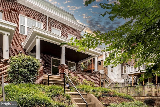 view of front of home featuring brick siding and fence