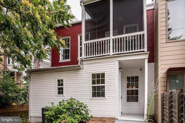 rear view of property featuring a balcony and brick siding