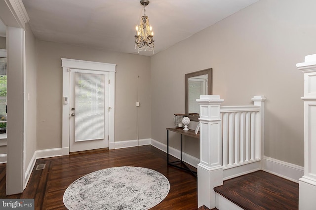 foyer entrance with dark wood-style flooring, baseboards, and an inviting chandelier