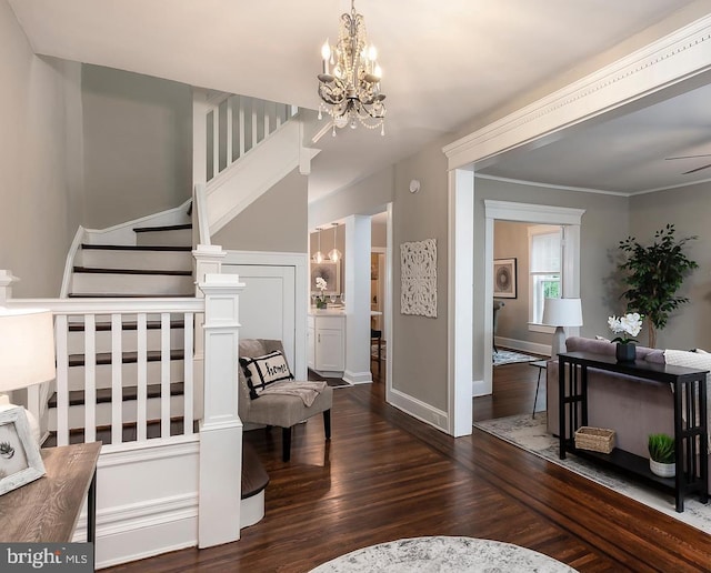 foyer entrance with crown molding, dark wood finished floors, an inviting chandelier, baseboards, and stairs