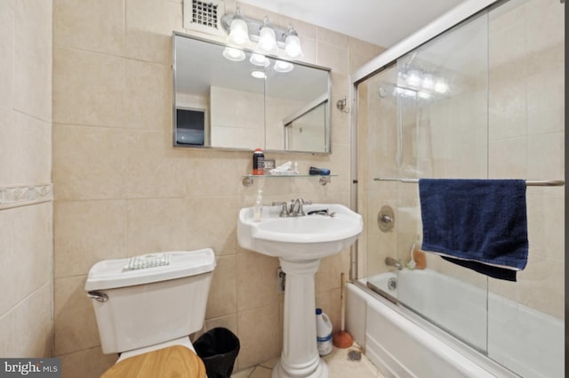 bathroom featuring toilet, tile walls, and enclosed tub / shower combo