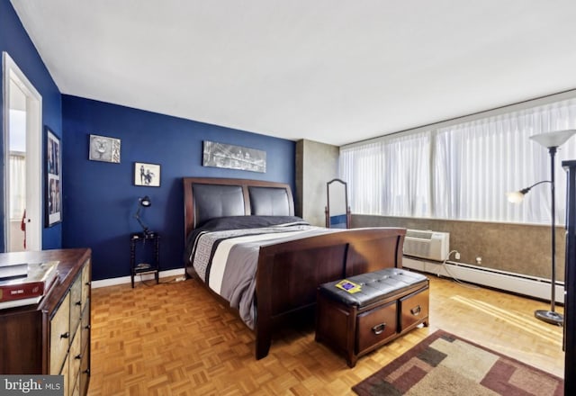 bedroom with light parquet floors, a wall unit AC, and a baseboard radiator