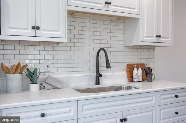 kitchen featuring decorative backsplash, white cabinetry, light countertops, and a sink