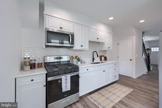 kitchen featuring light countertops, appliances with stainless steel finishes, a sink, and white cabinetry