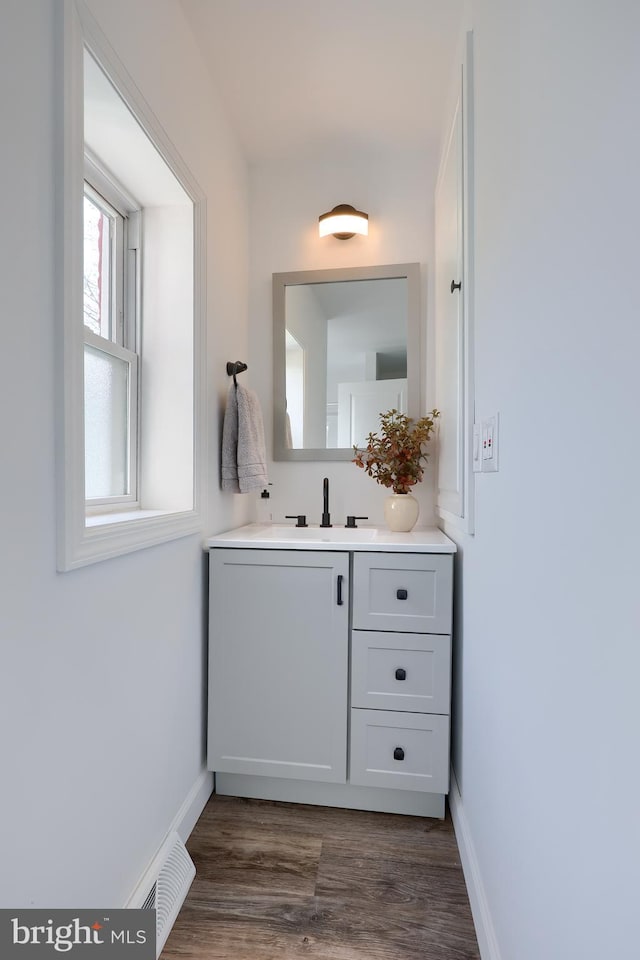 bathroom featuring visible vents, vanity, baseboards, and wood finished floors