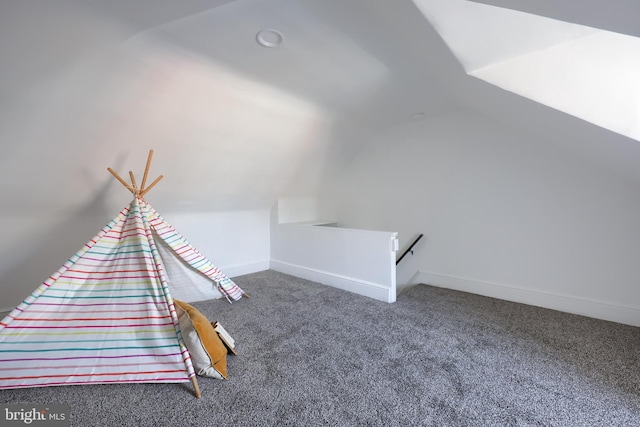 game room with vaulted ceiling, dark carpet, and baseboards