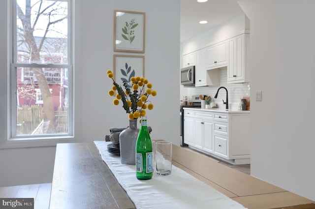 kitchen featuring stainless steel appliances, a sink, white cabinets, light countertops, and decorative backsplash