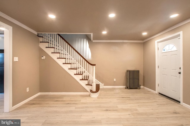 entrance foyer featuring light wood-type flooring, ornamental molding, radiator heating unit, and stairway