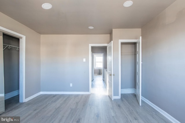 unfurnished bedroom with a closet, light wood finished floors, and baseboards