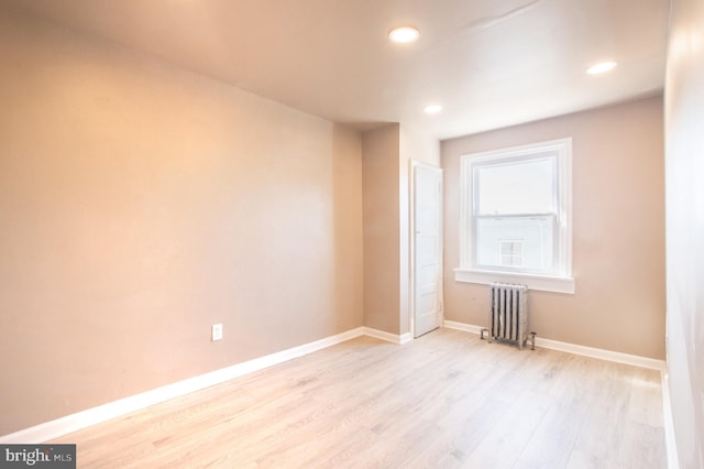 spare room featuring recessed lighting, baseboards, wood finished floors, and radiator heating unit