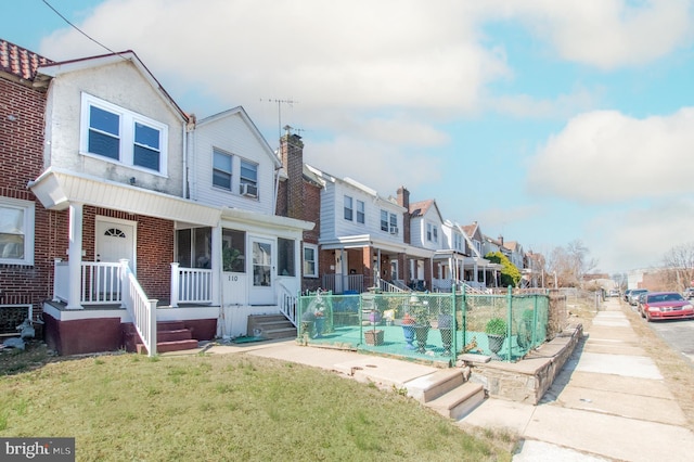 exterior space with brick siding, fence, a residential view, a porch, and a yard