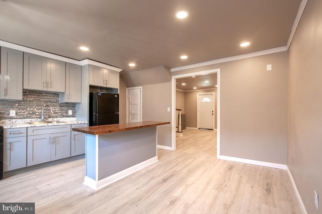 kitchen featuring freestanding refrigerator, gray cabinetry, a sink, wood counters, and backsplash