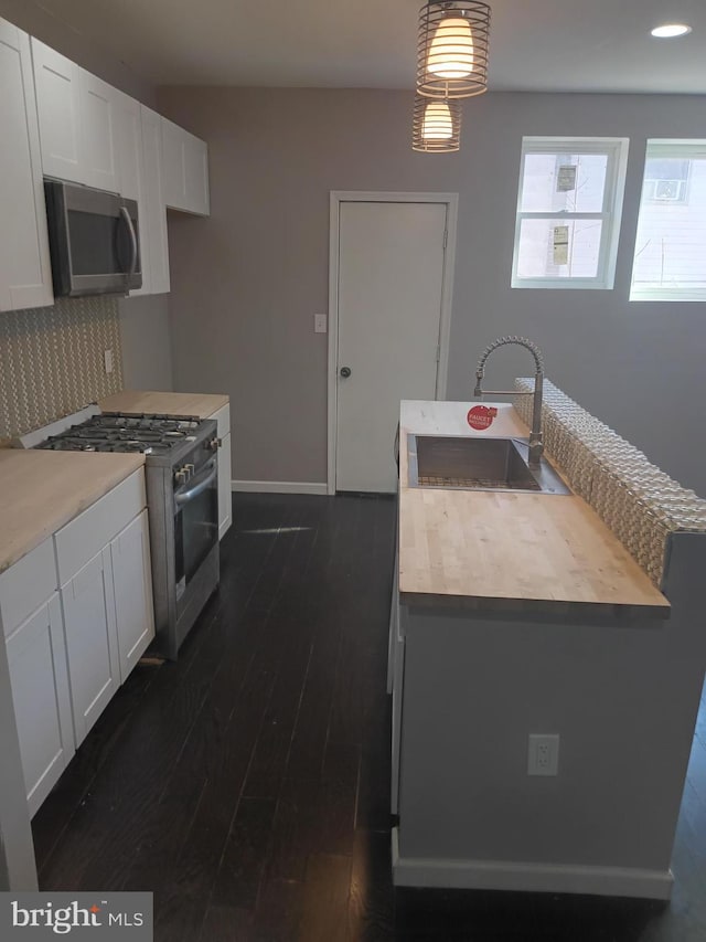 kitchen featuring decorative light fixtures, sink, white cabinets, dark hardwood / wood-style flooring, and stainless steel appliances