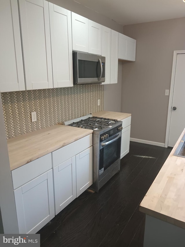 kitchen featuring butcher block countertops, stainless steel appliances, and white cabinets