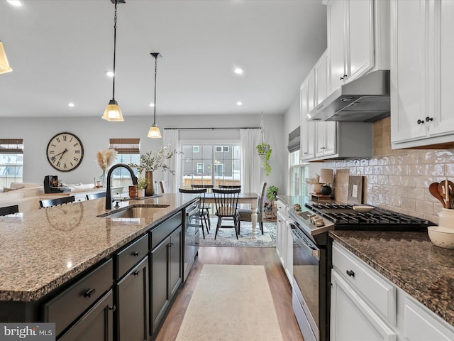 kitchen with sink, white cabinetry, decorative light fixtures, appliances with stainless steel finishes, and an island with sink