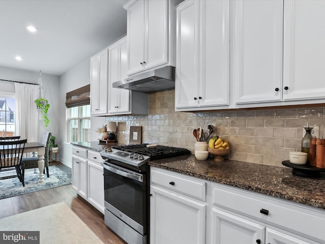 kitchen featuring dark stone countertops, white cabinets, hardwood / wood-style flooring, plenty of natural light, and stainless steel range with gas stovetop