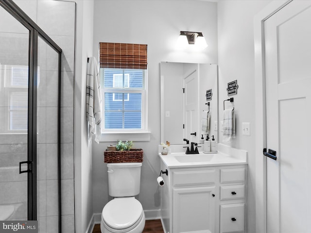 bathroom featuring vanity, a shower with door, and toilet