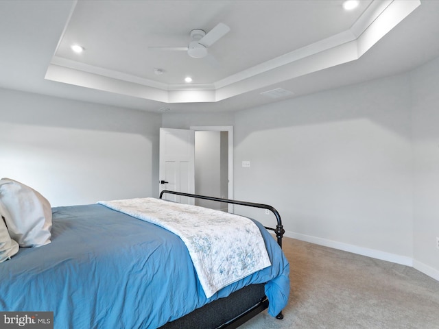 bedroom with light carpet, a tray ceiling, and ceiling fan