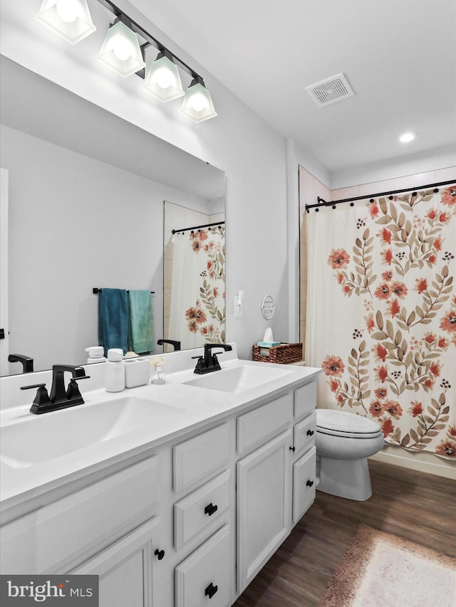 full bathroom featuring vanity, hardwood / wood-style floors, shower / tub combo with curtain, and toilet