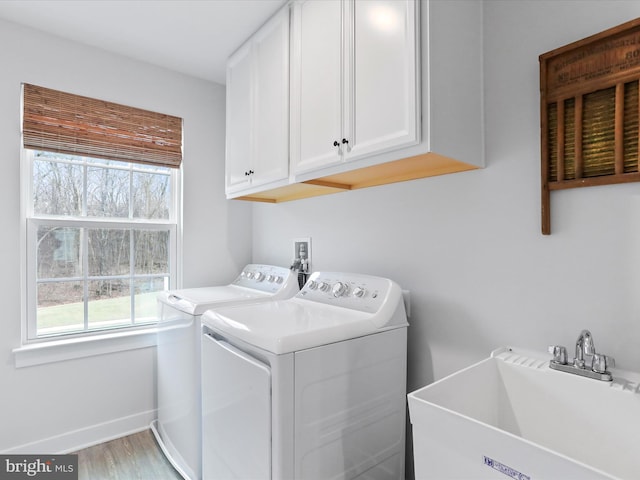 washroom with sink, wood-type flooring, washing machine and dryer, and cabinets