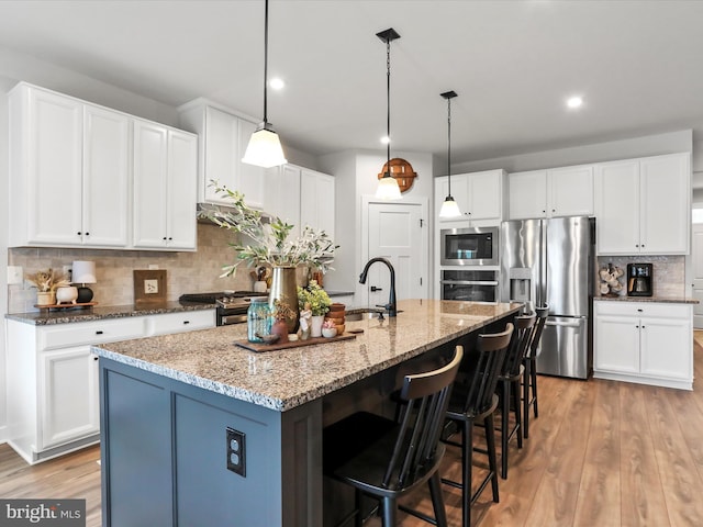 kitchen featuring white cabinetry, appliances with stainless steel finishes, and an island with sink