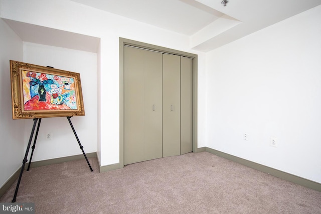 unfurnished bedroom featuring light colored carpet and a closet