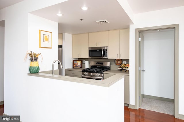 kitchen featuring stainless steel appliances, sink, kitchen peninsula, and cream cabinets