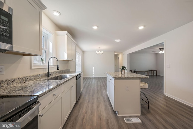 kitchen with sink, hanging light fixtures, stainless steel appliances, a center island, and white cabinets