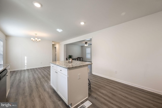 kitchen with a kitchen island, pendant lighting, white cabinets, light stone counters, and dark wood-type flooring