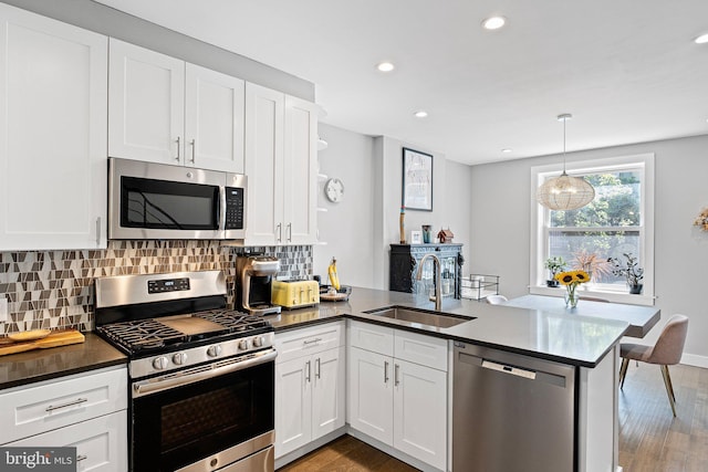 kitchen featuring appliances with stainless steel finishes, kitchen peninsula, sink, and white cabinets