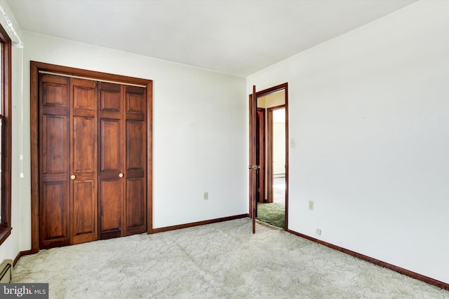 unfurnished bedroom featuring a closet, a baseboard radiator, and light carpet