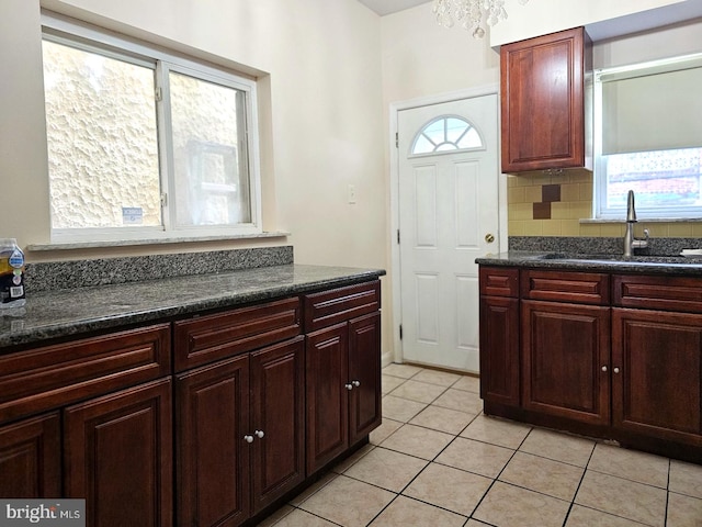 kitchen with tasteful backsplash, sink, dark stone countertops, and light tile patterned flooring