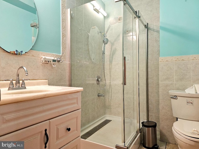 bathroom featuring vanity, toilet, a shower with door, and tile walls