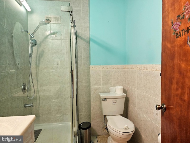 bathroom featuring an enclosed shower, vanity, tile walls, and toilet