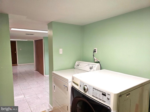 laundry room featuring washing machine and dryer and light tile patterned floors