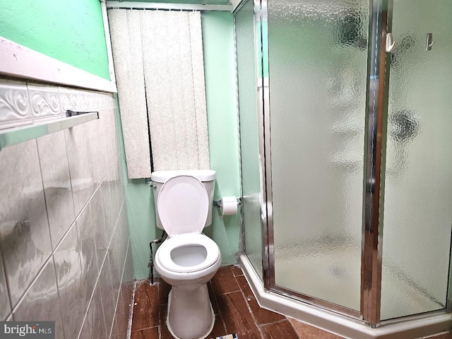 bathroom featuring walk in shower, tile walls, and toilet