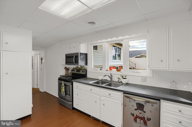 kitchen with sink, dark wood-type flooring, stainless steel appliances, and white cabinets