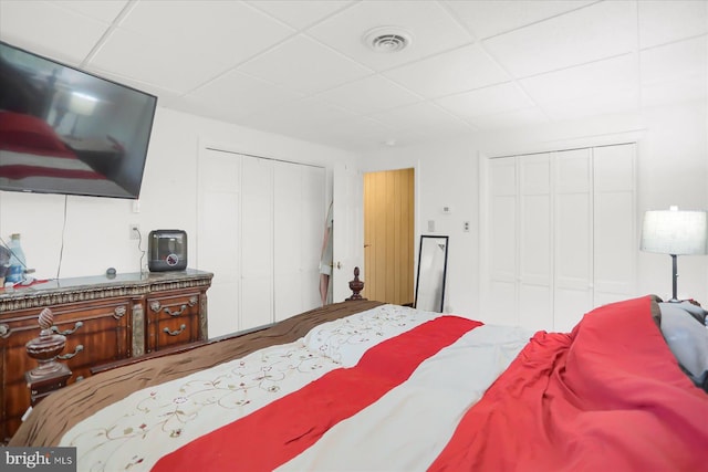 bedroom with multiple closets and a paneled ceiling