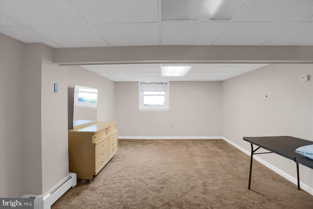 basement with baseboard heating, a paneled ceiling, and carpet floors