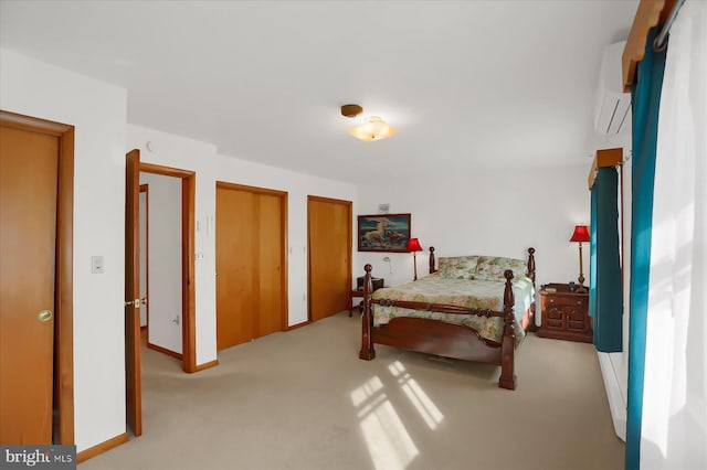 bedroom featuring multiple closets, a wall mounted air conditioner, and light carpet