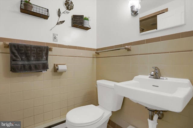 bathroom featuring tile walls, sink, and toilet